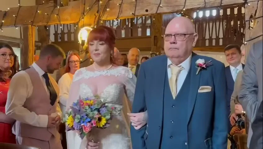 Ash walking down the aisle of a fairy-lit timber barn